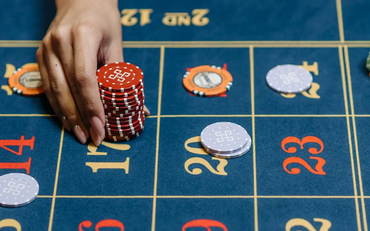 Hand placing a stack of casino chips on a betting layout – PHFUN wagering