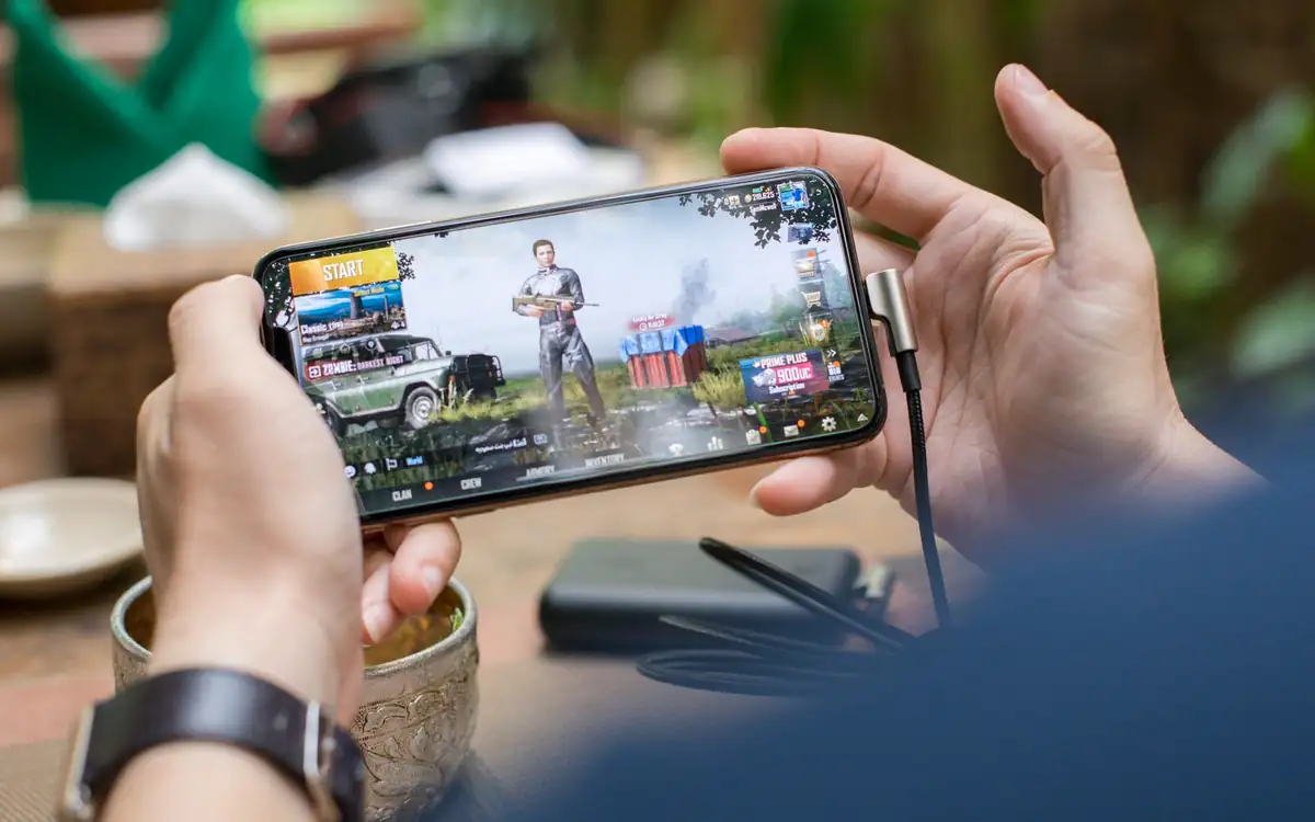 Hands holding a smartphone in landscape mode playing a game – PHFUN app