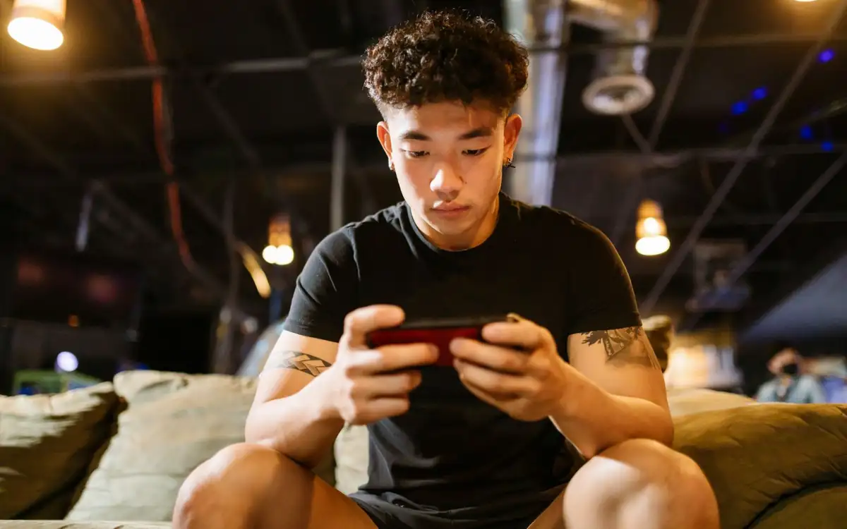 Young Asian player focused on a mobile game – playing PHFUN on a smartphone